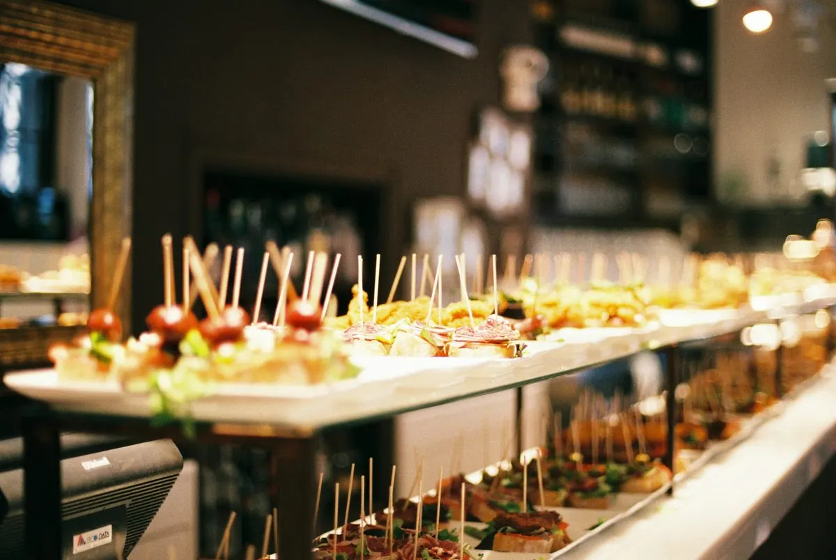 Balcão de aperitivos e canapés servidos em espetinhos, em ambiente de bar aconchegante