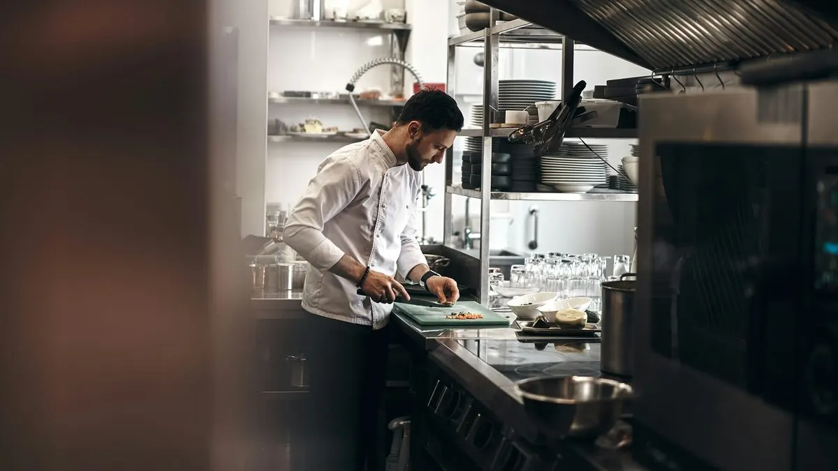Chef finalizando pratos em evento noturno, com iluminação dourada ao fundo